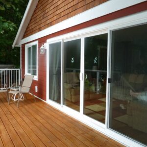 A red house with cedar shakes and a large glass door with white siding and trim.