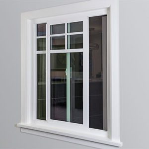 A slider window with white trim on a grey house.