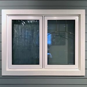 Casement windows with white trim on a blue-grey house.