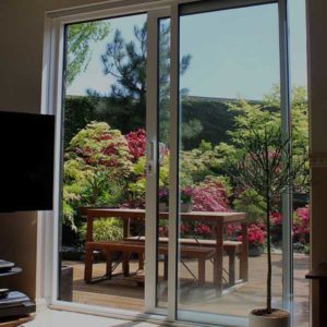 A glass door with screen, outlooking onto a garden and patio.