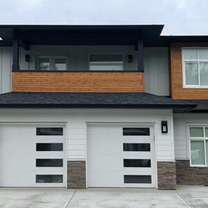 A modern pacific-northwest style house with grey, white and black colours and wood accents.