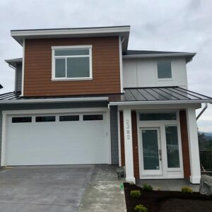 Modern house and entry doors with metal roof, and brown, white and grey siding.